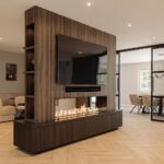 Luxe cinewall met haard in decoratief plaatmateriaal combinatie LR81 Sable en LR21 Sable in donker noten hout in woonkamer met industriële stalen schuifdeuren