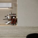 Detailafbeelding van een bar uitgewerkt in plaatmateriaal FD01 Taranta van Cleaf, welke de beleving van travertin heeft. De wandafwerking uitgewerkt in een zandkleurig decor FD10 Taranta van Cleaf.