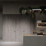 Een render van een horecagelegenheid met een bar uitgewerkt in het donkergrijze plaatmateriaal FD16 Taranta van Cleaf in combinatie met een blad uitgewerkt in het gekorrelde solid surface decor TS053 Old Castle van Durasein. De wandafwerking uitgewerkt in het lichtgrijze decor FD16 Taranta van Cleaf met een deur in de S212 Corteccia, welke de beleving van gerookt grijs kastanjehout biedt.