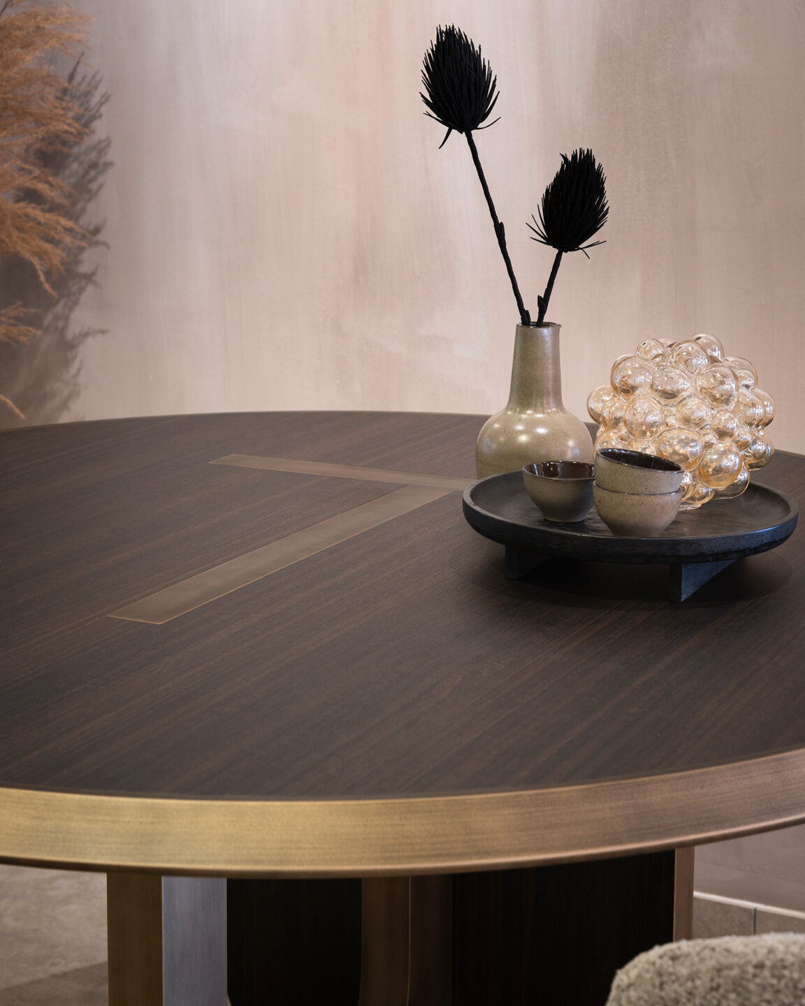 Closeup van de Icon tafel van Tio die is gemaakt met decoratief plaatmateriaal van DecoLegno in donkerbruine kleur LR29 Sablé, met metalfinish rand met bloem in vaasje