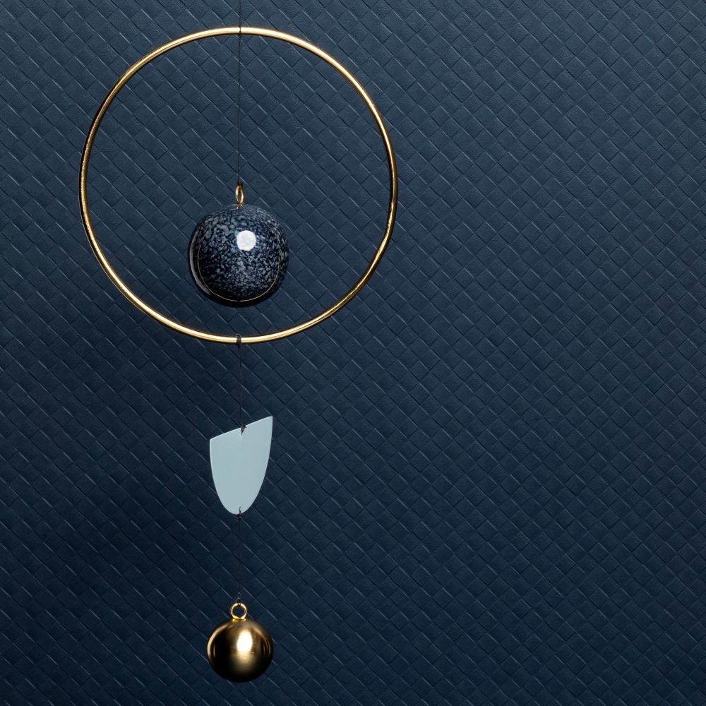 Sfeerbeeld van de UB02 Ares van Cleaf, een donkerblauw variant met leer structuur met gouden decoratieve hanger in de voorgrond