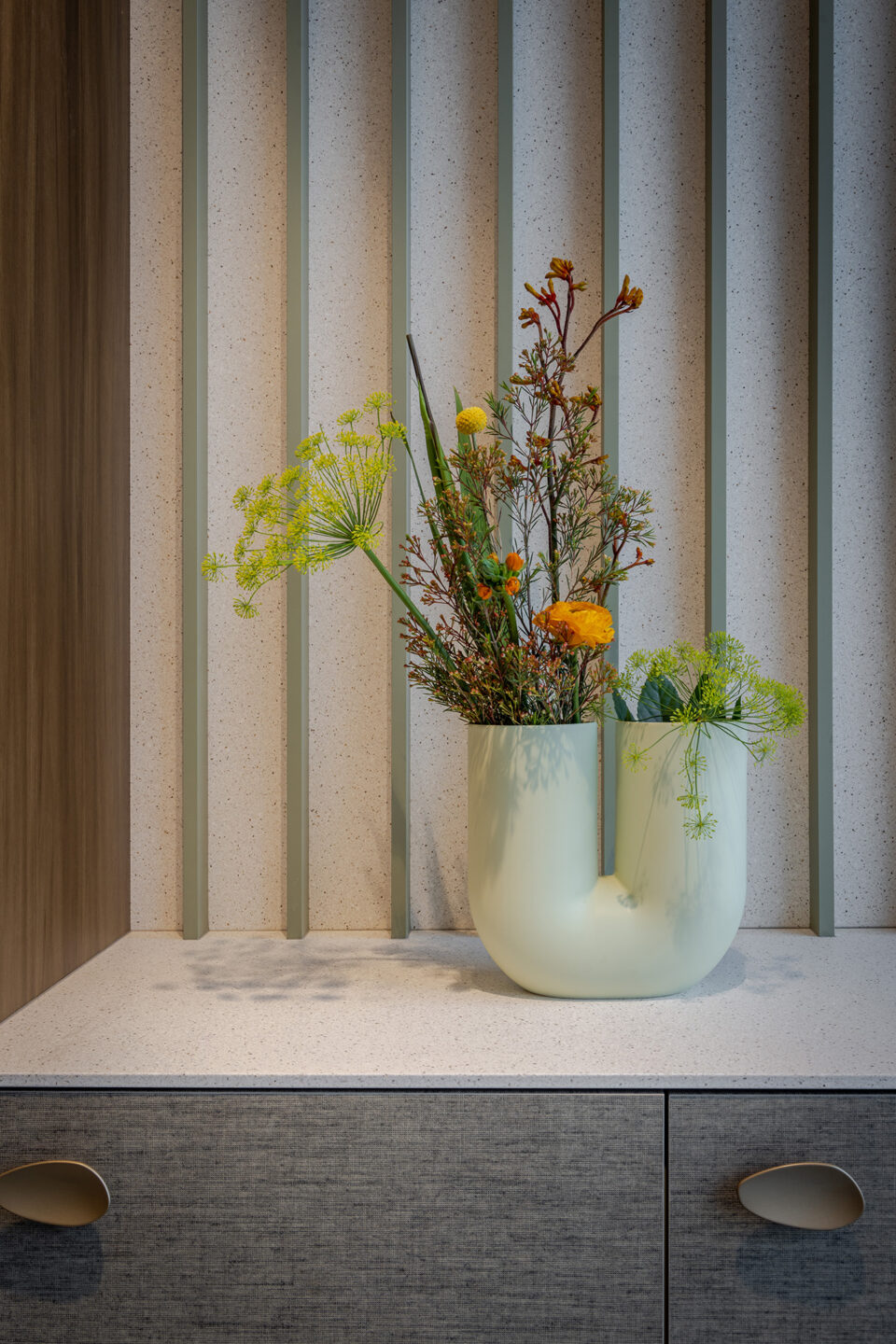 Dressoirkast met u-vormige vaas en bos gekleurde bloemen