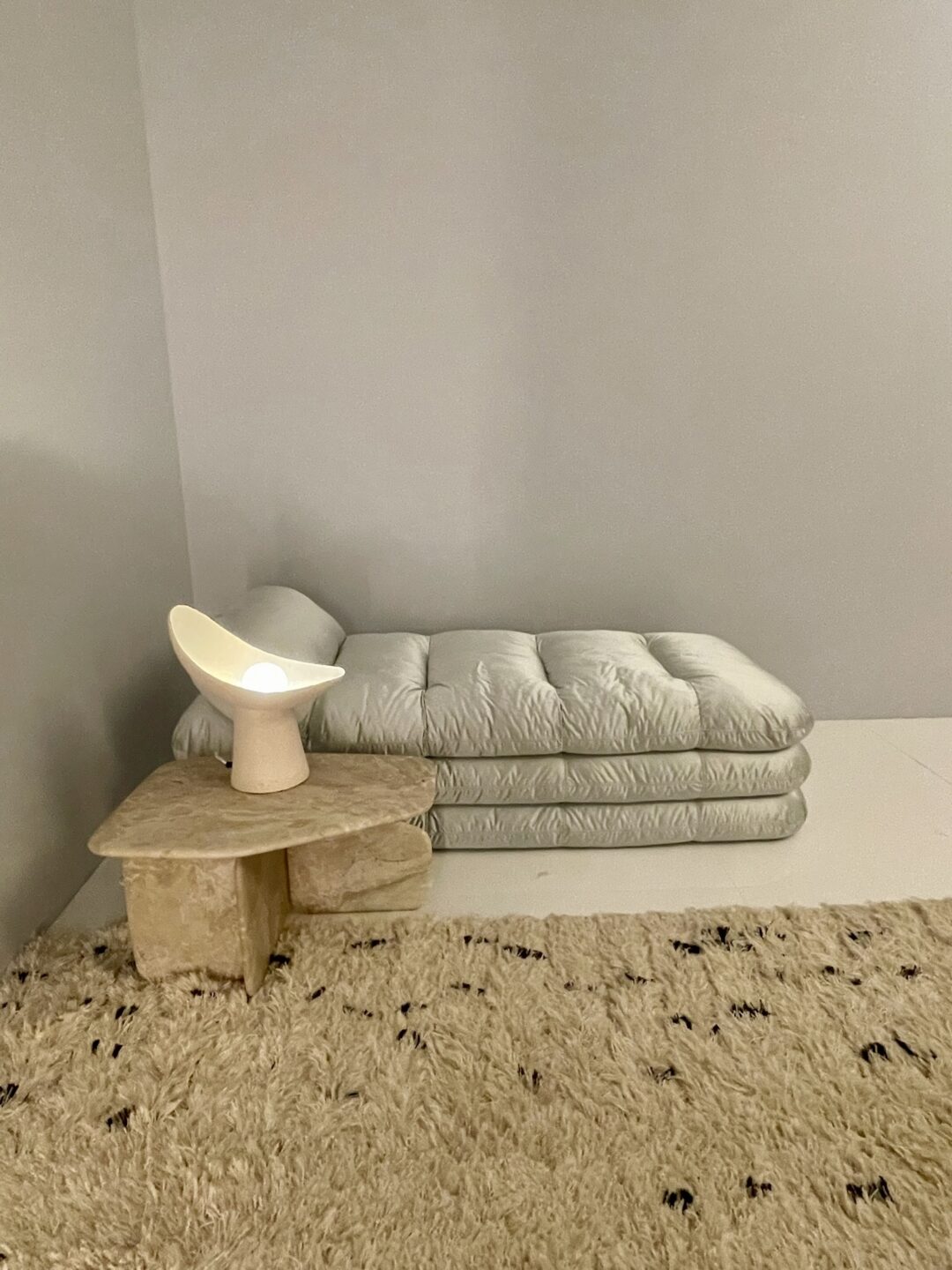 Daybed van Faye Toogood voor Tacchini met groot kleed, ronde bijzettafel en designlamp