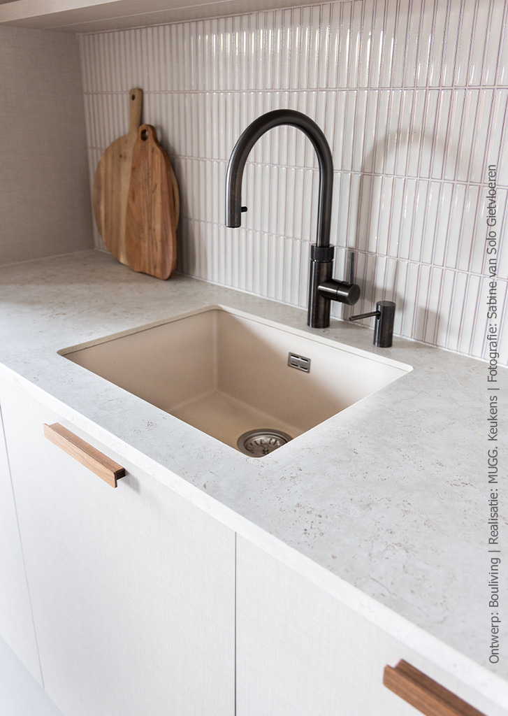 Closeup beeld van een keuken uitgevoerd in decoratief plaatmateriaal met linnenstructuur in FA44 Penelope in lichtbeige met op de achterwand langwerpige beige tegels