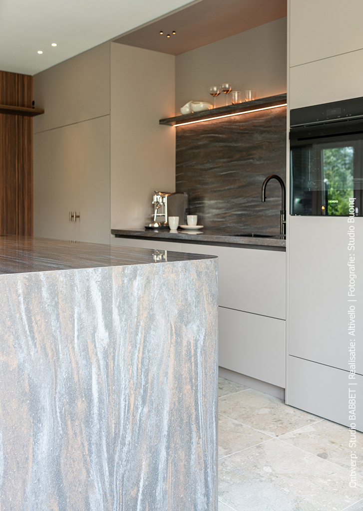 Keuken met kookeiland in warmbruin solid surface DM5004 Volcano met steenrode en grijze nuances, taupekleurige kasten in UA94 Talco en wandafwerking in Pallisanderdecor LK00 Matrix met voelbare houtnerf