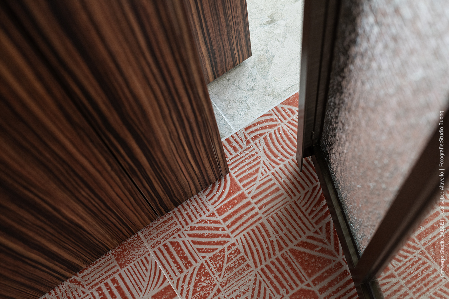 Detail van maatwerk wandafwerking in Pallisanderdecor LK00 Matrix, in combinatie met grafisch rood vloertegelpatroon